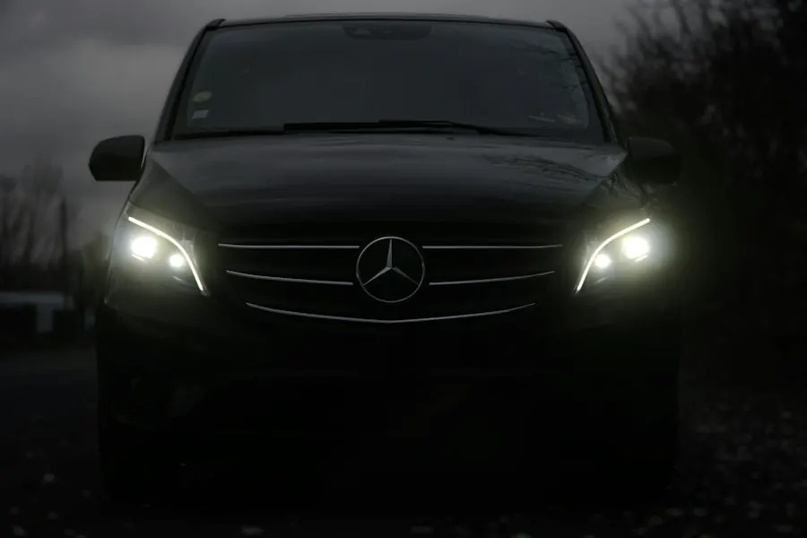 Black Mercedes van with headlights on at night